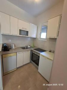 a small kitchen with white cabinets and a sink at Topla in Herceg-Novi