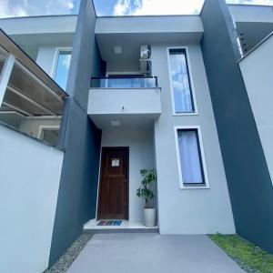 a facade of a house with a door and a plant at Casa completa com 2 quartos e garagem perto do aeroporto in Joinville