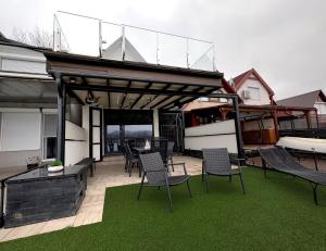 a patio with chairs and a deck with a roof at RestOnTheLake in Esztergom