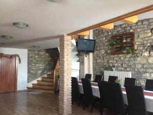 a dining room with a table and chairs and a stone wall at Atkári Vendégház in Bóly