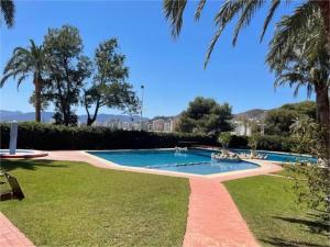 a swimming pool in a park with trees and grass at Cullera - Primera Línea de Playa in Faro de Cullera
