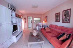 a living room with a red couch and a tv at Cullera - Primera Línea de Playa in Faro de Cullera