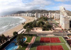 a view of a beach with buildings and a tennis court at Cullera - Primera Línea de Playa in Faro de Cullera