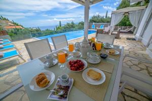 a table with breakfast foods and orange juice on it at Villa Hera-The infinity blue in Nisaki
