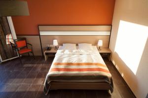 a bedroom with a bed with an orange wall at Hotel Lacotel in Avenches