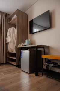 a room with a small refrigerator and a tv on the wall at GuestHouse-Medeu in Almaty