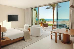 a bedroom with a bed and a view of the beach at The Red Sea EDITION in Ḩanak