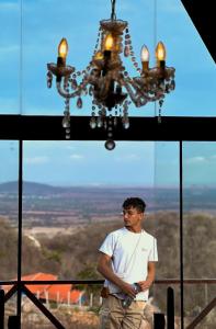 a man standing in front of a chandelier at Chalé serra da formiga in Riachuelo