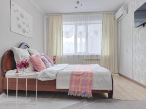 a bedroom with a bed and a window and a table at Nectar Apartments in Aktobe