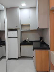 a kitchen with white cabinets and black counter tops at Residencial Ibiapaba in Camocim
