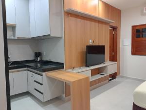 a kitchen with white cabinets and a flat screen tv at Residencial Ibiapaba in Camocim