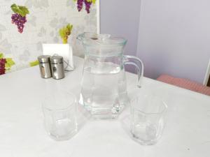 a glass pitcher and two glasses on a table at Nectar Apartments in Aktobe