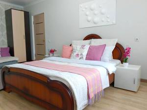 a bedroom with a large bed with pink and white pillows at Nectar Apartments in Aktobe