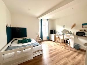 a bedroom with a bed and a kitchen with a table at Le Blue- hyper centre ville in Sens