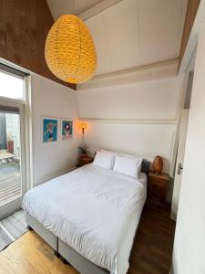 a bedroom with a white bed and a pendant light at At Loum in Alkmaar