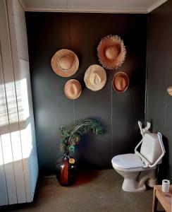 a bathroom with a toilet and straw hats on the wall at Llama Lodge Authentic Sunnfjord Farm in Kleivane