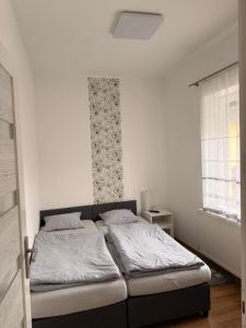 a bedroom with a bed with white sheets and a window at BE-LE-VALÓ APARTMAN in Szécsény