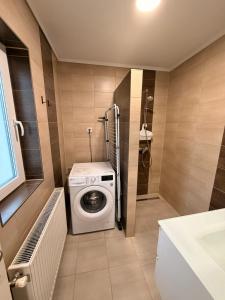 a bathroom with a washing machine and a shower at BE-LE-VALÓ APARTMAN in Szécsény