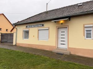 a yellow building with a white door and a garage at BE-LE-VALÓ APARTMAN in Szécsény
