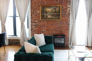 a living room with a green couch and a brick wall at The Luxe Building- 2 Bedroom Apartment in Metropolis in Metropolis