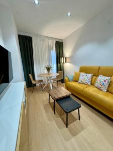 a living room with a yellow couch and a table at CAROLINA CENTRO SUITEs in Monesterio