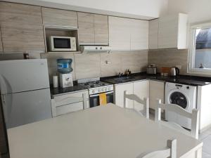 a kitchen with white appliances and a table in it at Duplex De Los Padres in Playa Unión +8 photos