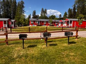 a row of red houses in a field with benches at The Red Station Apartment #1 in Columbia Falls