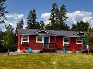 a red house with chairs on a yard at The Red Station Apartment #1 in Columbia Falls