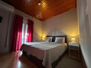 a bedroom with a large bed with red curtains at Tsonas Apartments in Lygia