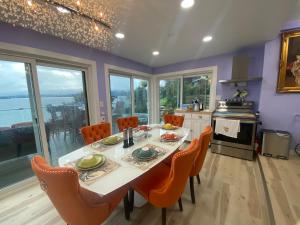 a dining room with a table and chairs and a kitchen at Stunning oceanfront home 4br3b sunrise beachcombing near Bamberton Park in Mill Bay