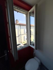 a bathroom with a toilet and a window at petit studio atypique in Graulhet