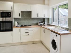 a kitchen with white cabinets and a washer and dryer at Number 23 in Wooler +9 photos