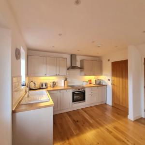 a kitchen with white cabinets and a wooden floor at Chy Bownder Cottage in Lostwithiel