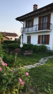 a house with a balcony and a bench and flowers at Cascina Garaita in Fossano