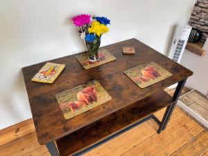 a wooden table with a vase of flowers on it at The Sandbed Retreat in Hawick