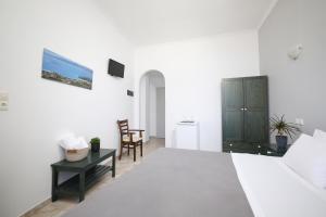 a white bedroom with a bed and a desk at Angeliki Seaside Hotel in Aliki