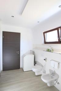 een witte badkamer met 2 toiletten en een wastafel bij Messewohnung Rehdorf in Oberasbach +7 foto's
