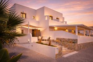 a large white house with a sunset in the background at Aegeeis in Perissa