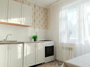 a kitchen with white cabinets and a stove and a window at 11 Microragion in Aktobe
