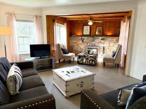 a living room with couches and a stone fireplace at Cozy Farm House with River access in Three Rivers
