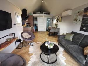 a living room with a couch and a table at Tiny Haus Auszeit am See in Lathum