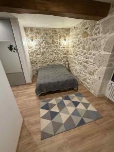 a bedroom with a bed and a stone wall at Au rêve de Fadi in Bruch