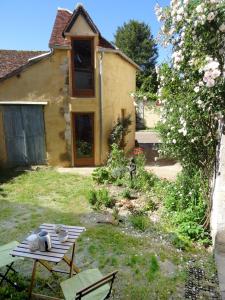 a garden with a table and a house at L'Escalier des Rêves - Rose in Saint-Sauveur-en-Puisaye