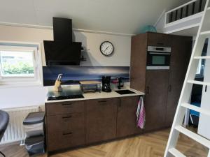 a kitchen with a stove and a clock on the wall at Tiny Haus Auszeit am See in Lathum +16 photos