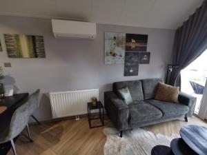 a living room with a couch and a table at Tiny Haus Auszeit am See in Lathum