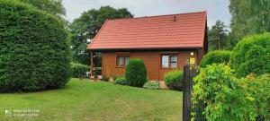 a small house with a red roof in a yard at Rodzinny Domek Ruś in Ruś