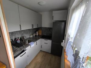 a small kitchen with white cabinets and a black refrigerator at Rodzinny Domek Ruś in Ruś
