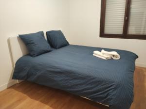 a bed with blue sheets and two towels on it at Charming Bagneux Nest in Bagneux