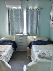 a bedroom with two beds and a dresser and a window at La casa de Nimia in Asunción