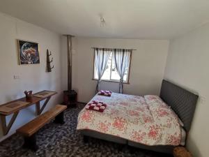 a bedroom with a bed and a table and a window at tiny house kiñeco melipeuco conguillio in Santa María